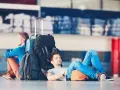 Dwóch mężczyzn z bagażami czeka na lotnisku. Jeden śpi, drugi czuwa. Zastanawiasz się, ile wcześnie być na lotnisku?