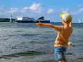 Kind winkt einem großen Schiff in Flensburg zu. Ein toller Ausflug mit Kindern, auch wenn es mal regnet.