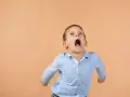 Bambino con espressione di forte frustrazione, con bocca spalancata e pugni chiusi. Un'immagine che evoca la necessità di capire come calmare un bambino autistico.