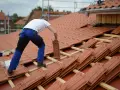 Operaio posa tegole su tetto in fase di rifacimento. Stima quanto costa rifare un tetto di 200 mq.