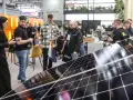 Ludzie zwiedzają targi energii odnawialnej, oglądając panele słoneczne i stoiska firm.