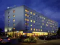 Ibis Budget Warszawa Centrum nocą. Hotel z podświetlanym logo, oknami i parkingiem.
