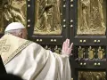 Papst Franziskus berührt die heilige Pforte des Petersdoms. Die bronzene Tür ist mit Reliefs verziert, die biblische Szenen darstellen.
