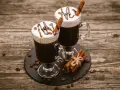 Dwa Irish coffee z bitą śmietaną, polewą czekoladową i laską cynamonu. Jaki to smak? Słodki, kawowy, z nutą alkoholu i przypraw.