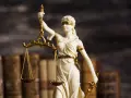 Temida z wagą i mieczem, symbol sprawiedliwości, na tle starych ksiąg. Może symbolizować e-sąd w Lublinie.