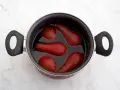 Olla con peras al vino tintas, listas para ser un postre delicioso.