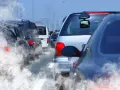 Tráfico denso con humo saliendo de los coches, reflejando la contaminación.