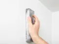 Mano lijando una pared blanca para reparar grietas en techo de yeso.