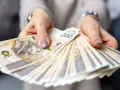Dłonie trzymające plik banknotów 200 zł. Pytanie o to, ile zarabia hotelarz, często wiąże się z takimi widokami.