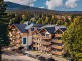 Nowoczesny hotel z drewnianymi balkonami w otoczeniu jesiennego lasu. Idealne noclegi Szklarska Poręba dla miłośników gór.