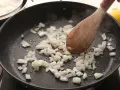 Cebolla picada se sofríe en una sartén, parte de unas deliciosas recetas con cebolla. Arroz blanco y mariscos esperan.