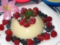 Panna cotta z malinami i borówkami, posypana cukrem pudrem. Idealny legumina przepis na deser.