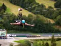 Kobieta w kasku leci na tyrolce, doświadczając adrenaliny na najdłuższej tyrolce w Polsce.