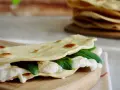 Piadina fatta in casa ripiena di mozzarella filante e spinacini freschi, pronta per essere gustata.