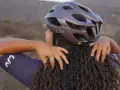 Donna con dreadlocks che regola un casco da bici Liv. Non preoccuparti se il tuo casco è stretto, ci sono modi per allargare il casco stretto.