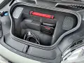 Otwarty bagażnik Porsche Macan z kablem do ładowania, apteczką i instrukcją.