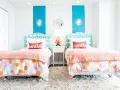 Dos camas gemelas en habitación pequeña, con cabeceros estampados y colchas naranjas. ¡Una solución genial para como poner dos camas en una habitacion pequeña!