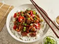 Schüssel mit Reis und einem köstlichen Chicken Teriyaki, garniert mit Frühlingszwiebeln und Sesam.