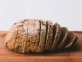 Pokrojony bochenek chleba razowego na desce. Zastanawiasz się, ile kalorii ma chleb razowy?
