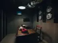 Mörkt rum med skrivbord, gamla telefoner, skrivmaskin och flera klockor på väggen. Perfekt för en spännande escape room hemma-upplevelse.