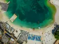 Widok z lotu ptaka na plażę w Albanii. Turkusowa woda, leżaki, parasole i łodzie. Idealne miejsce na albania wakacje 2026.