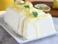 Un delizioso semifreddo al limone, guarnito con scorzette, menta e una glassa gialla brillante, pronto per essere gustato.
