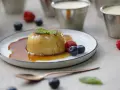Delicioso flan de queso con caramelo, adornado con menta y frutos rojos.