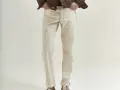Uomo con giacca marrone e jeans chiari. La vestibilità è slim, non skinny, con risvolti alla caviglia.
