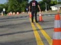 Osoba ustawia pachołki na placu manewrowym. Zastanawiasz się, ile kosztuje egzamin teoretyczny na prawo jazdy?