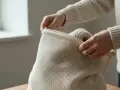 Händerna drar igen en tvättpåse med en stickad tröja inuti, för att undvika att ullen krymper i tvätten.