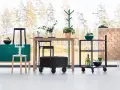 Inredning med en grön skänk, träbord, svarta pallar och en rullvagn. Design från a2 designers.