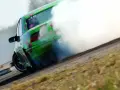 Zielony samochód z kwiatami driftuje, wydzielając dużo dymu.