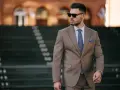 Elegancki mężczyzna w garniturze, z niebieską poszetką w kieszonce marynarki, na tle schodów.