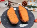 Dos mitades de boniato al horno, tiernas y doradas, con hierbas picadas y una cucharada de crema.