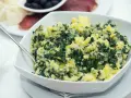 Un tazón blanco lleno de acelgas con patatas, un plato casero y reconfortante.