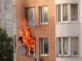 Flammen schlagen aus einem Fenster eines Mehrfamilienhauses. Ein trauriger Anblick, besonders wenn man bedenkt, dass es sich um einen wohnungsbrand ohne hausratversicherung handelt.