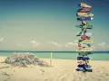 Strand mit Schildern zu fernen Zielen. Ein Traum für ein **auslandsjahr kostenlos**?