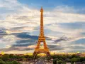 Le symbole de la Tour Eiffel se dresse fièrement sous un ciel nuageux, illuminé par les rayons du soleil couchant.