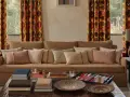 Cortinas con estampado geométrico vibrante, un sofá acogedor y cojines texturizados. Las ultimas tendencias cortinas salon se reflejan en este espacio.