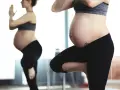 Ciężarna kobieta w czarnych legginsach i sportowym topie ćwiczy, odbijając się w lustrze. To może być jej sposób na aktywną zumbę w ciąży.