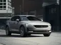 Srebrny Polestar 2 jedzie ulicą miasta, z nowoczesnymi budynkami w tle.