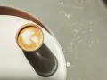 Idealna kawa flat white z pianką w kształcie liścia, podana na tacy.