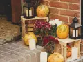 Gemütliche herbstdeko hauseingang mit Kürbissen, Laternen und Blumen auf Holzkisten.