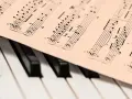 Partytura z nutami, być może suita w 18 wieku, leży na klawiaturze fortepianu.