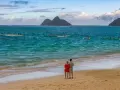 Para młoda na plaży, podziwiająca ocean i łodzie. Idealne miejsce na podróż poślubną.