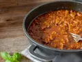 Un saporito ragù di anatra, ricetta veneta, pronto in padella con una forchetta. Profumo di basilico fresco.