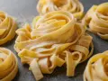 Nidi di tagliatelle fatte in casa, spolverate di farina, pronte per essere cucinate.