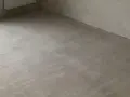 Świeżo wylana, szara krzywa wylewka samopoziomująca na podłodze, gotowa na dalsze prace wykończeniowe.
