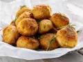 Un mucchio invitante di polpette in bianco, dorate e croccanti, guarnite con rosmarino fresco e sale grosso.