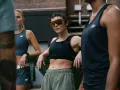Trzy kobiety w strojach sportowych, zastanawiające się, czy chodzenie odchudza. Jedna w okularach przeciwsłonecznych.